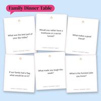 Six white Family Dinner Table cards scattered on light blue, including If our family had a flag, what would be on it? and What is the funniest joke you know? under a pink Family Dinner Table label
